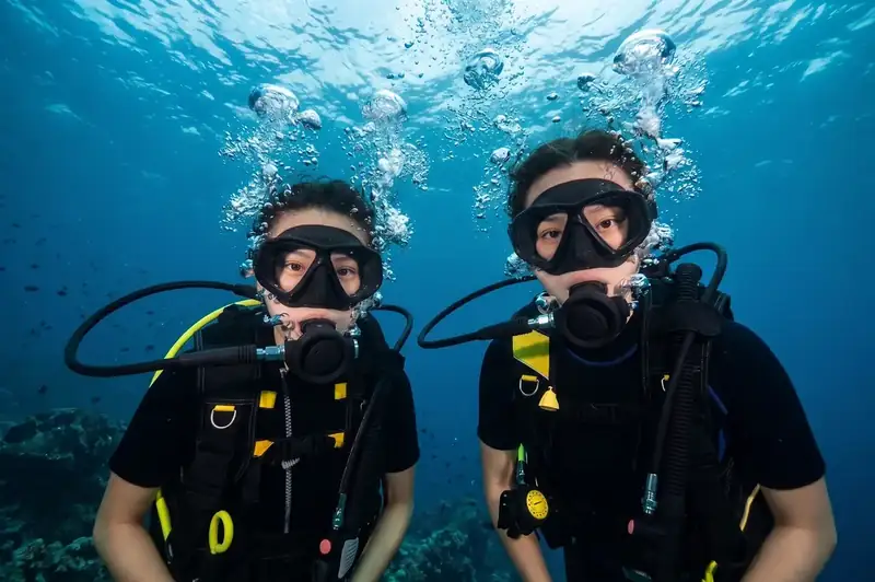 An expert dive buddy guiding scuba divers with Sisipan Island Resort near the Tun Sakaran Marine Park